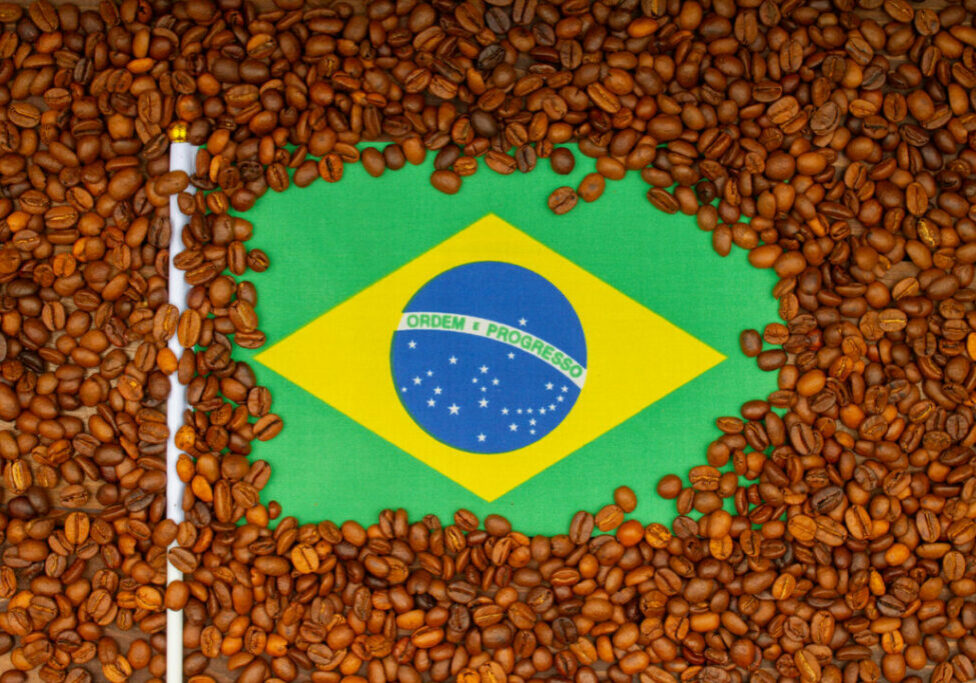 Roasted coffee beans and Brazilian flag on the table. Brazilian Coffee price rise concept. Arabica Coffee Futures Climb from Brazil. Top view. Close-up